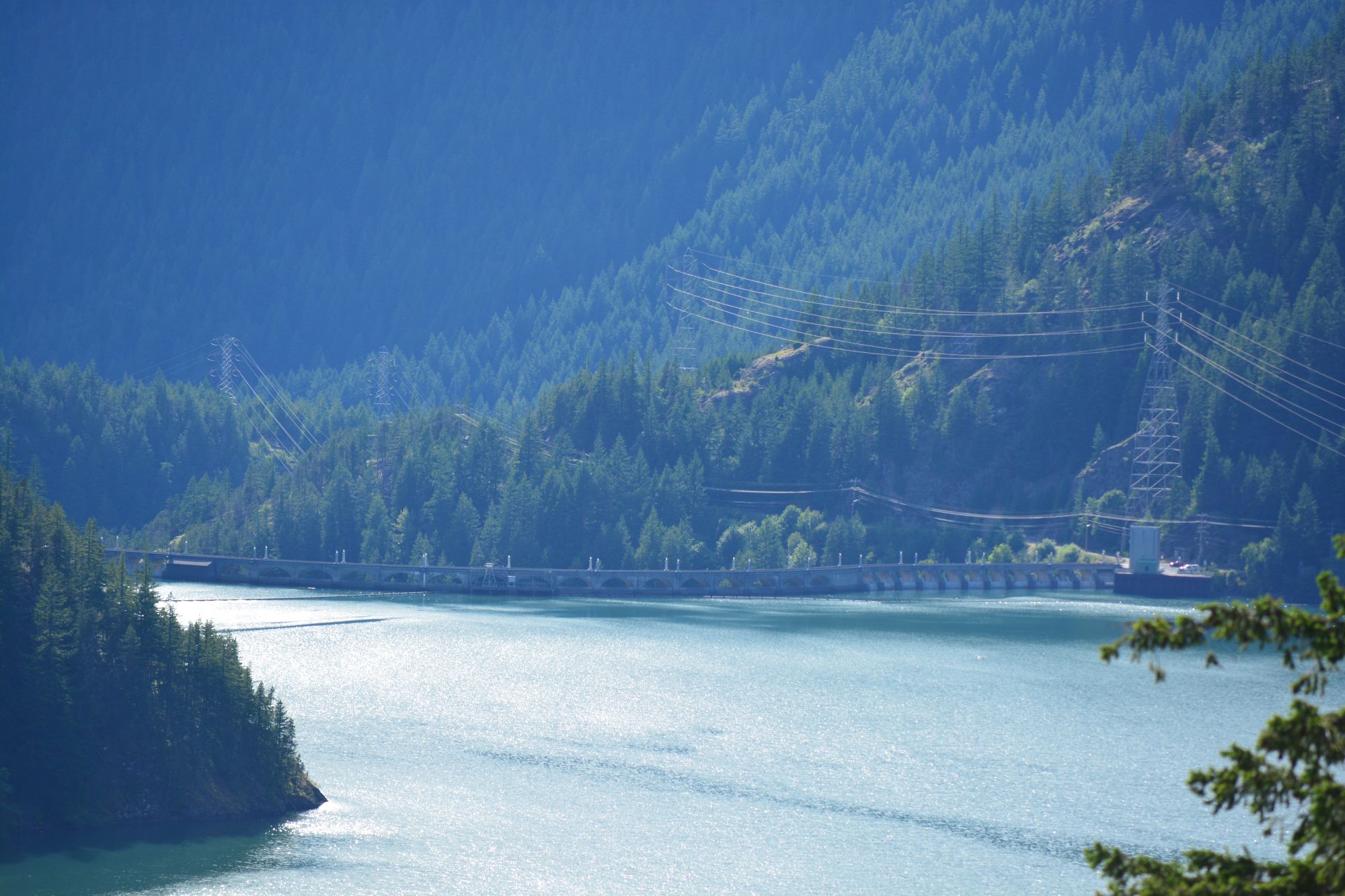 Diablo Lake seen from above with bright blue water, forested slopes, and the dam below
